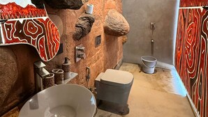 Une salle de bain avec un mur en pierre, un lavabo, des toilettes et un espace douche.