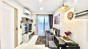 A modern living room with a sofa, a dining table, and a kitchen area. - A104- 1 Bedroom Serviced Apartment with Whirlpool at Ao Nang Beach (Tambon Ao Nang)
