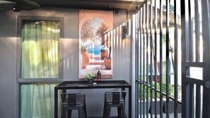 A balcony with a table, two chairs, a bottle, and a glass. - A103-  1 Bedroom Serviced Apartment with Whirlpool at Ao Nang Beach (Tambon Ao Nang)