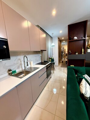 Une cuisine moderne équipée d’une cuisinière intégrée, d’un évier et d’un coin repas avec un canapé vert et une petite table.