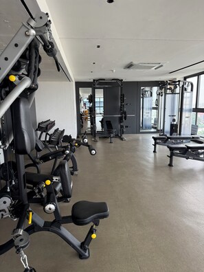 Une salle de sport équipée de divers appareils d’exercice, d’un banc de développé couché et d’un support à poids.
