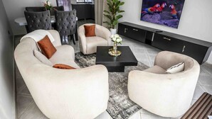 A modern living room with a sofa set, a coffee table, and a flat-screen TV. - Vo Homes, Modern Kisasi, Kulambiro kyanja Retreat  Quiet, Secure, WiFi Near City (KAMPALA)
