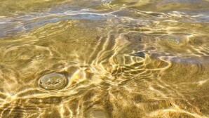 Una spiaggia con acque poco profonde che rivelano i disegni sulla sabbia.