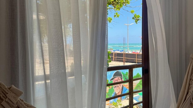 Un'amaca in una stanza con vista sulla spiaggia e un murale.
