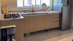 Una cucina moderna con un frigorifero in acciaio inossidabile, una stufa a gas, un lavello con rubinetto e una finestra sopra il lavello.