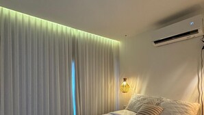 Una camera da letto con un letto, tende, un condizionatore e una lampada a parete.