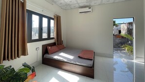 Ein Schlafzimmer mit Bett, Vorhängen, einer Klimaanlage und Blick nach draußen.