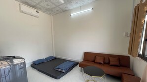 Ein Zimmer mit einer Couch, einem Bett, einem kleinen Tisch und einem Koffer.