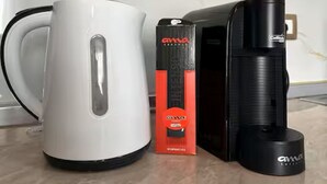 Ein weißes elektrisches Wasserkocher, eine rot-schwarze Reise-Espressomaschine und eine schwarze Reisekaffeemaschine auf einer Marmorarbeitsplatte.