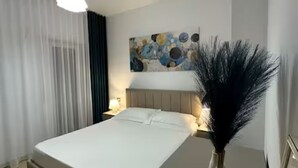 Ein modernes Hotelzimmer mit Bett, Nachttisch, Lampe, einem Gemälde an der Wand und einer dekorativen Vase.
