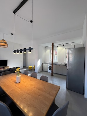 A modern kitchen with a stainless steel refrigerator, a dining area with a wooden table and chairs, and a hanging pendant light. - Old town apartment • central - quiet - Terrace - Parking lot - (Erfurt)