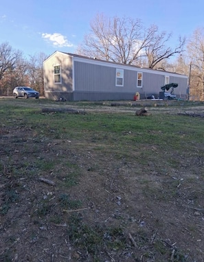 A single-story building with a flat roof, a small front porch, and a visible garage door. - 3-bedroom mobile home in charming Mount Pleasant with AC. (Mount Pleasant)
