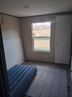 A room with a single window, a door, and a mattress on the floor. - 3-bedroom mobile home in charming Mount Pleasant with AC. (Mount Pleasant)