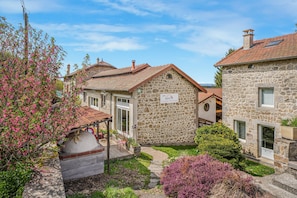 Um edifício de pedra com um jardim, um alpendre coberto e uma placa que diz 'Gîte Jardin Mirandon'.