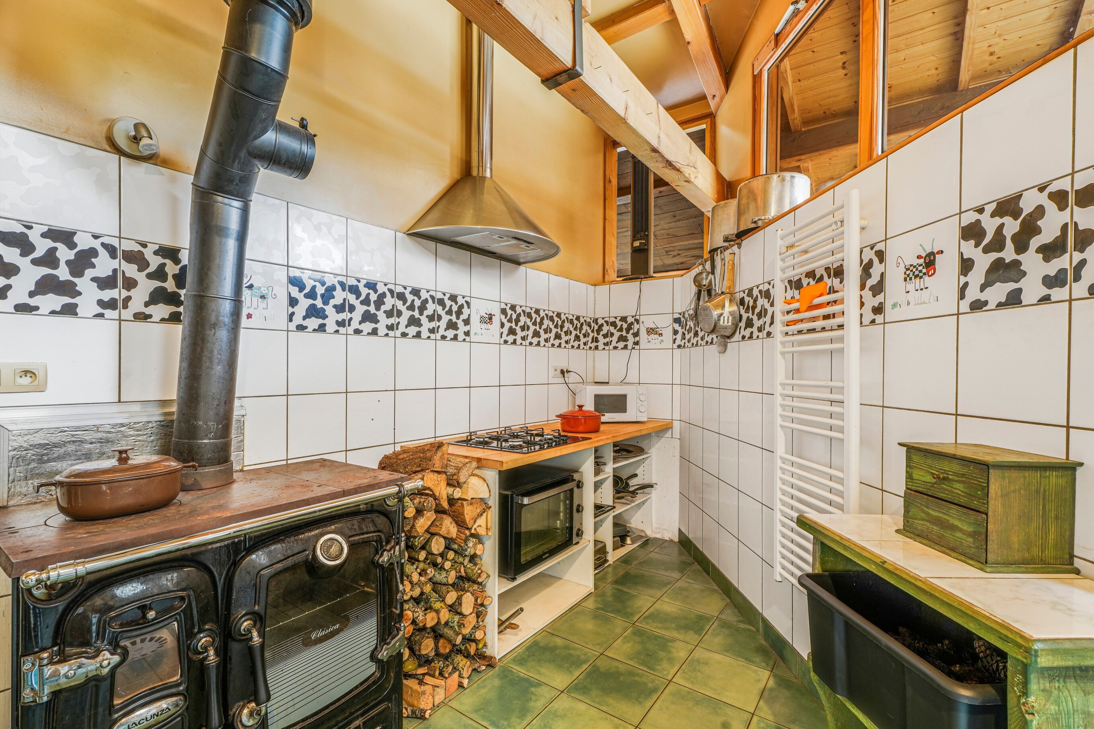 Una cucina con piano cottura, forno e pareti piastrellate.