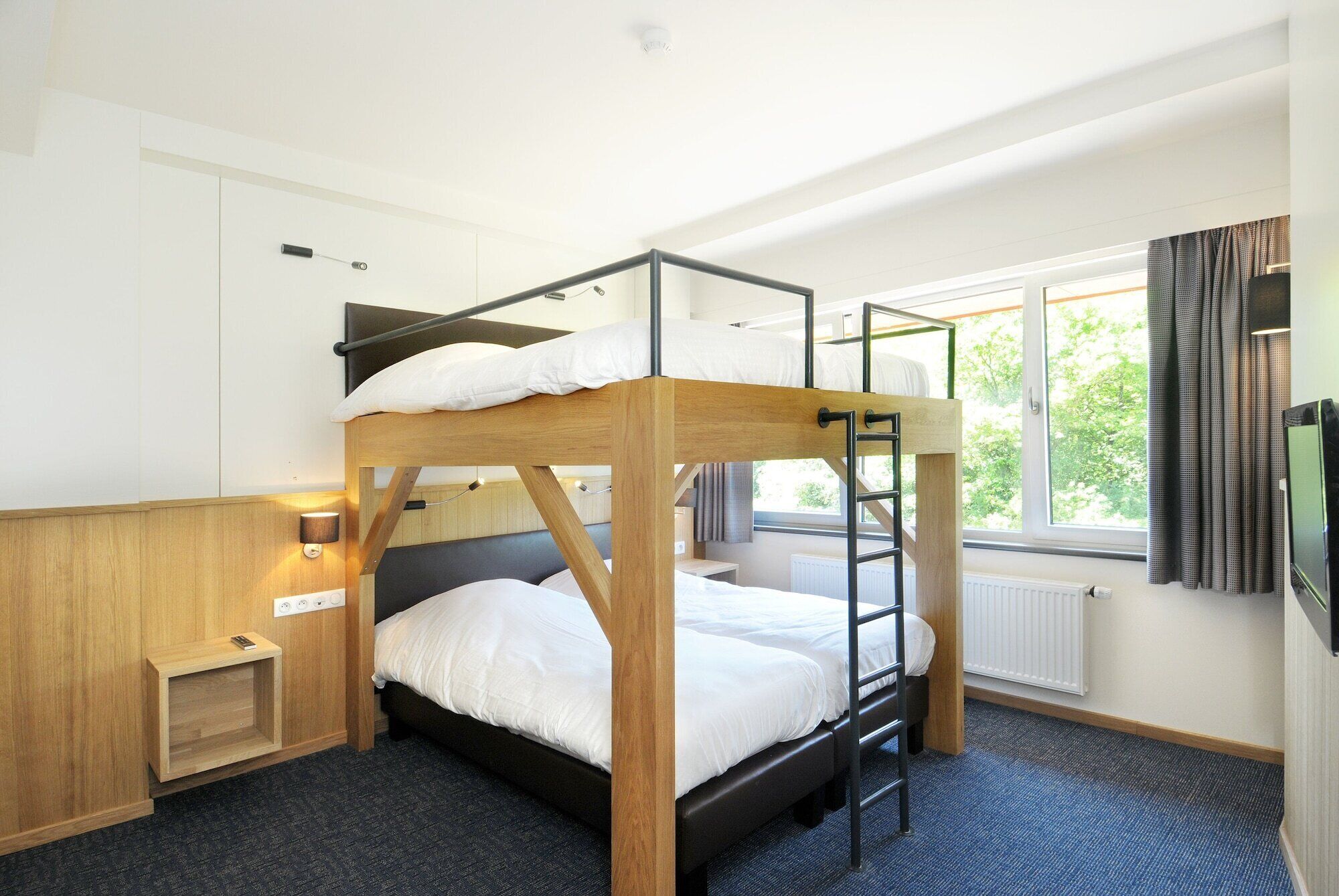 Une chambre avec un lit superposé, une échelle en bois, une petite table de chevet et une fenêtre avec des rideaux.
