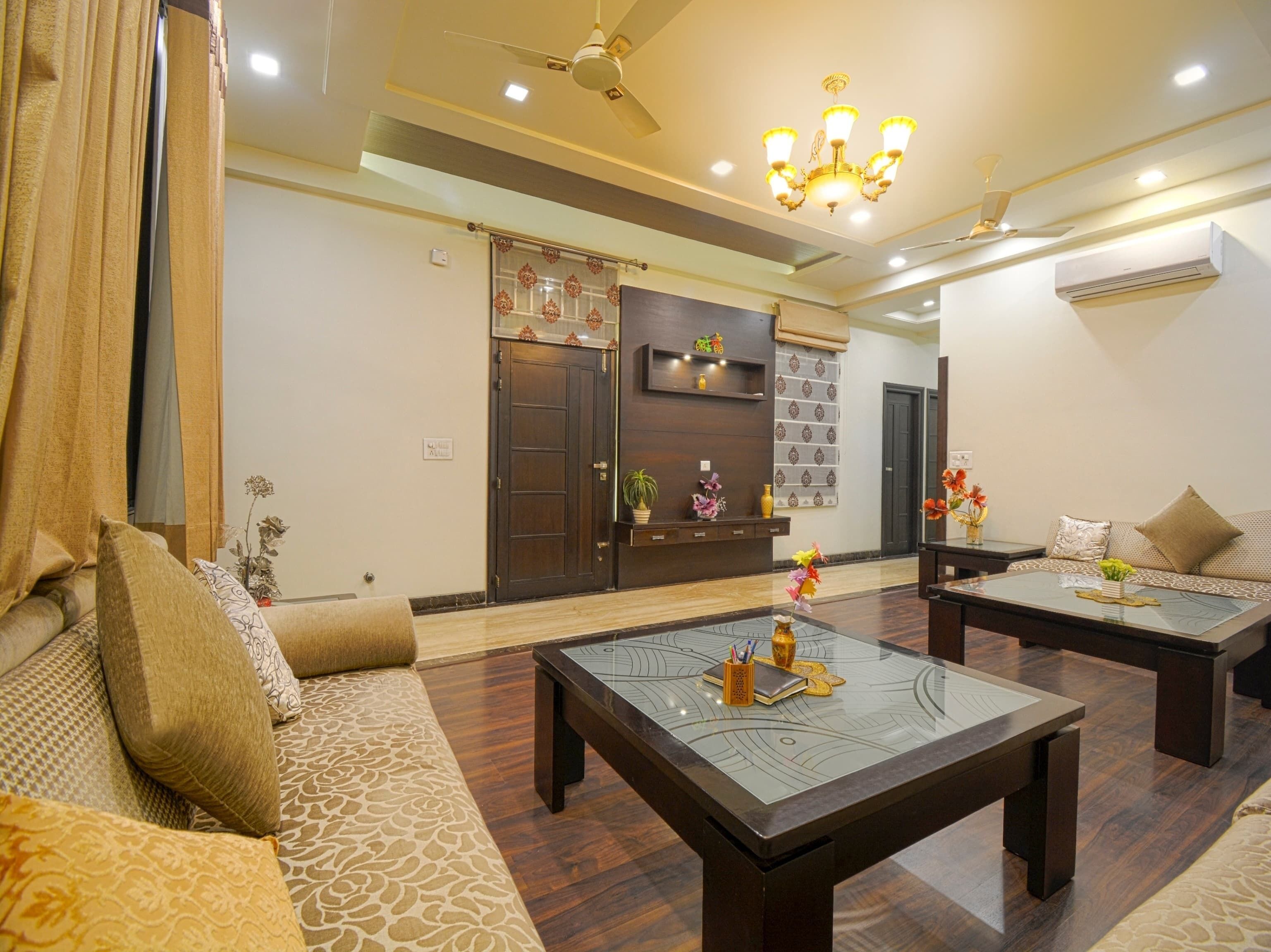 A living room with a sofa, two coffee tables, a chandelier, and a door with decorative panels.