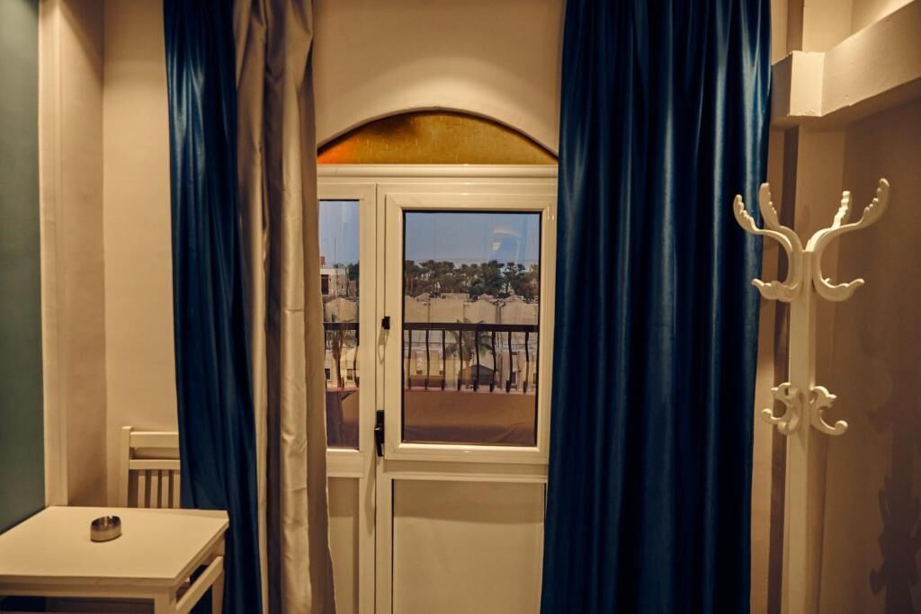 Una habitación con ventana, cortinas y perchero.