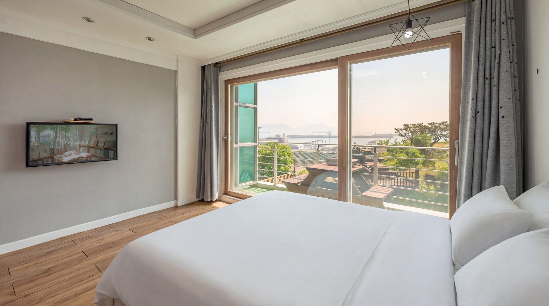 Un dormitorio con una cama grande, un televisor en la pared y un balcón con vistas.