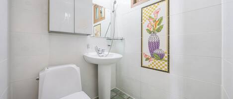 Un baño con inodoro, lavabo y ducha.
