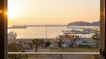 A coastal view with a marina, ships, and industrial buildings.