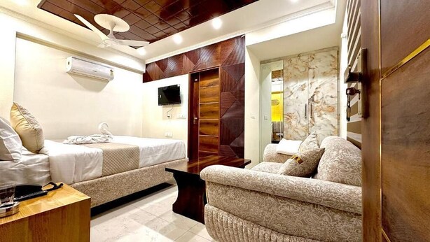 Una habitación de hotel con cama, sofá, televisión, aire acondicionado y armario de madera.