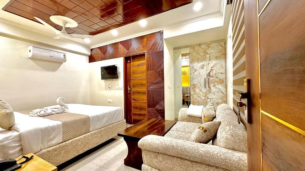 Ein Hotelzimmer mit Bett, Sofa, Fernseher und Kleiderschrank.