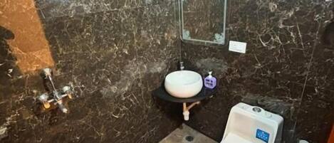 A bathroom with a sink, mirror, shower, and a toilet.