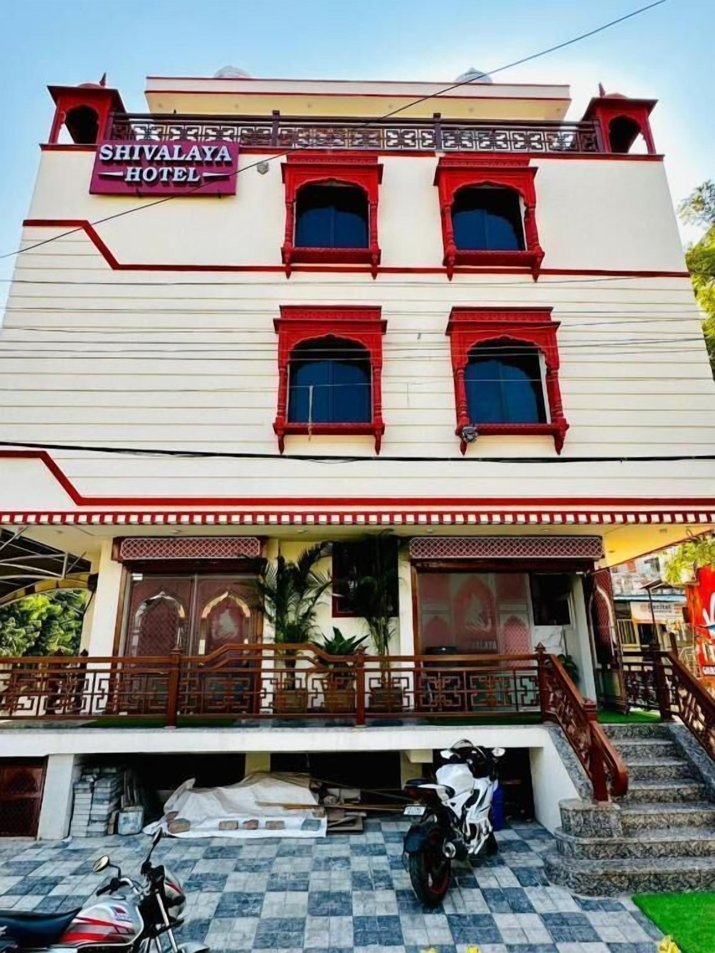 A hotel with a signboard, multiple windows, a covered entrance, and a staircase leading to the entrance.