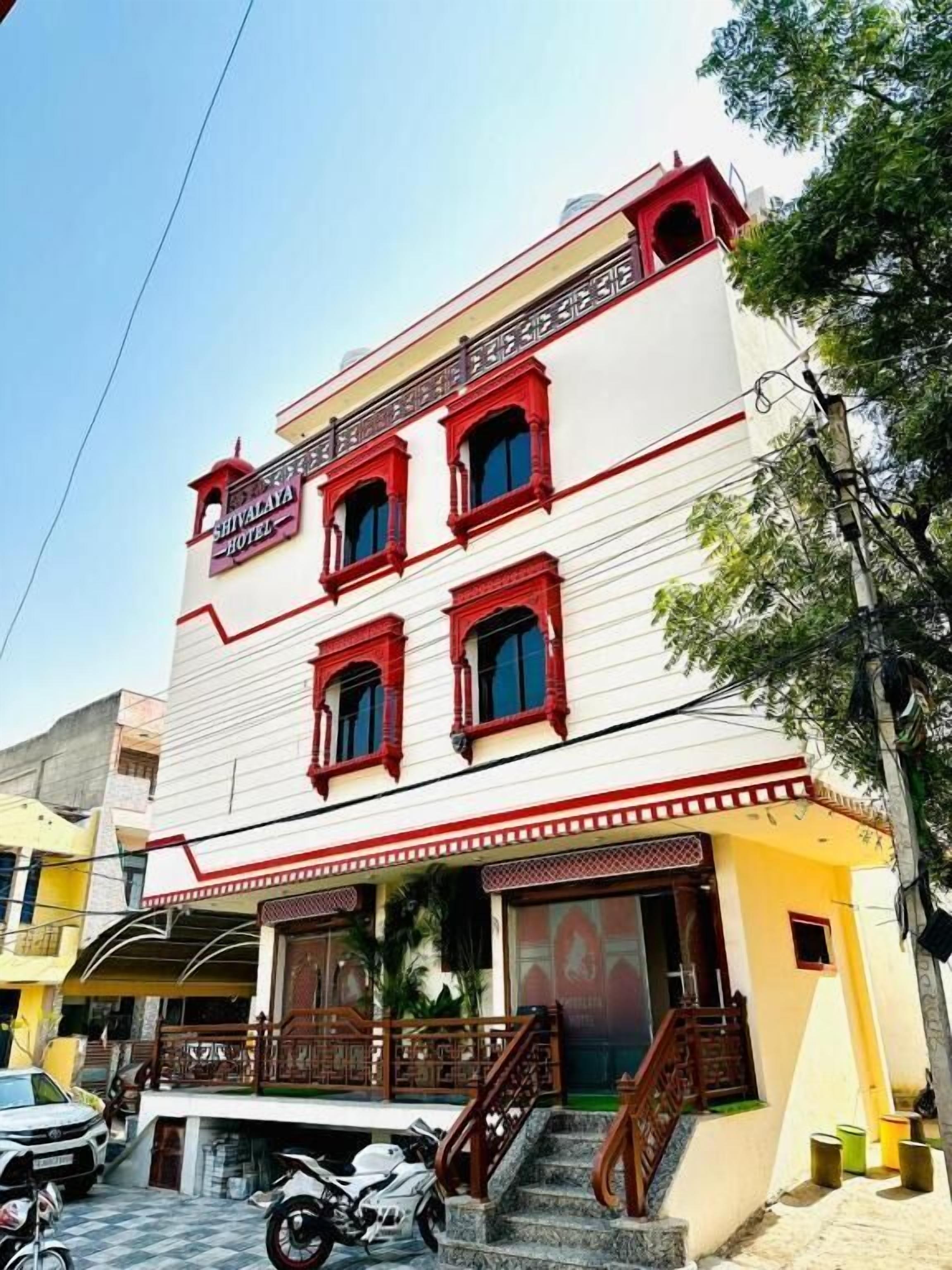 Ein mehrstöckiges Hotel mit roter und weißer Fassade, einem Balkon und einer Treppe, die zum Eingang führt.