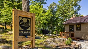 A cabin with a wooden sign, surrounded by rocks and trees. - Cabin at the Gap | You Won't Believe the View! (Harpers Ferry)