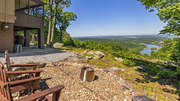 A modern building with a patio area, a fire pit, and a view of a river and forest. - Cabin at the Gap | You Won't Believe the View! (Harpers Ferry)