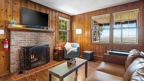A living room with a fireplace, a television, a couch, and large windows. - Cabin at the Gap | You Won't Believe the View! (Harpers Ferry)