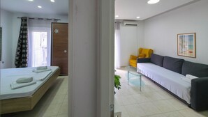Ein modernes Hotelzimmer mit einem Bett, einer Couch, einem Glastisch und einer Klimaanlage.