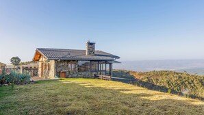 Una casa de piedra con techo metálico, ventanas grandes y vistas del paisaje.