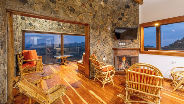 Una habitación con paredes de piedra, chimenea, muebles de madera y televisor.