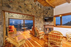 A stone-walled room with a fireplace, wooden furniture, and a television. - ol kinyaa cottage (Naivasha)