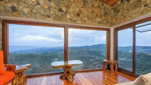 Una habitación con ventanas amplias, suelo de madera y mobiliario rústico.
