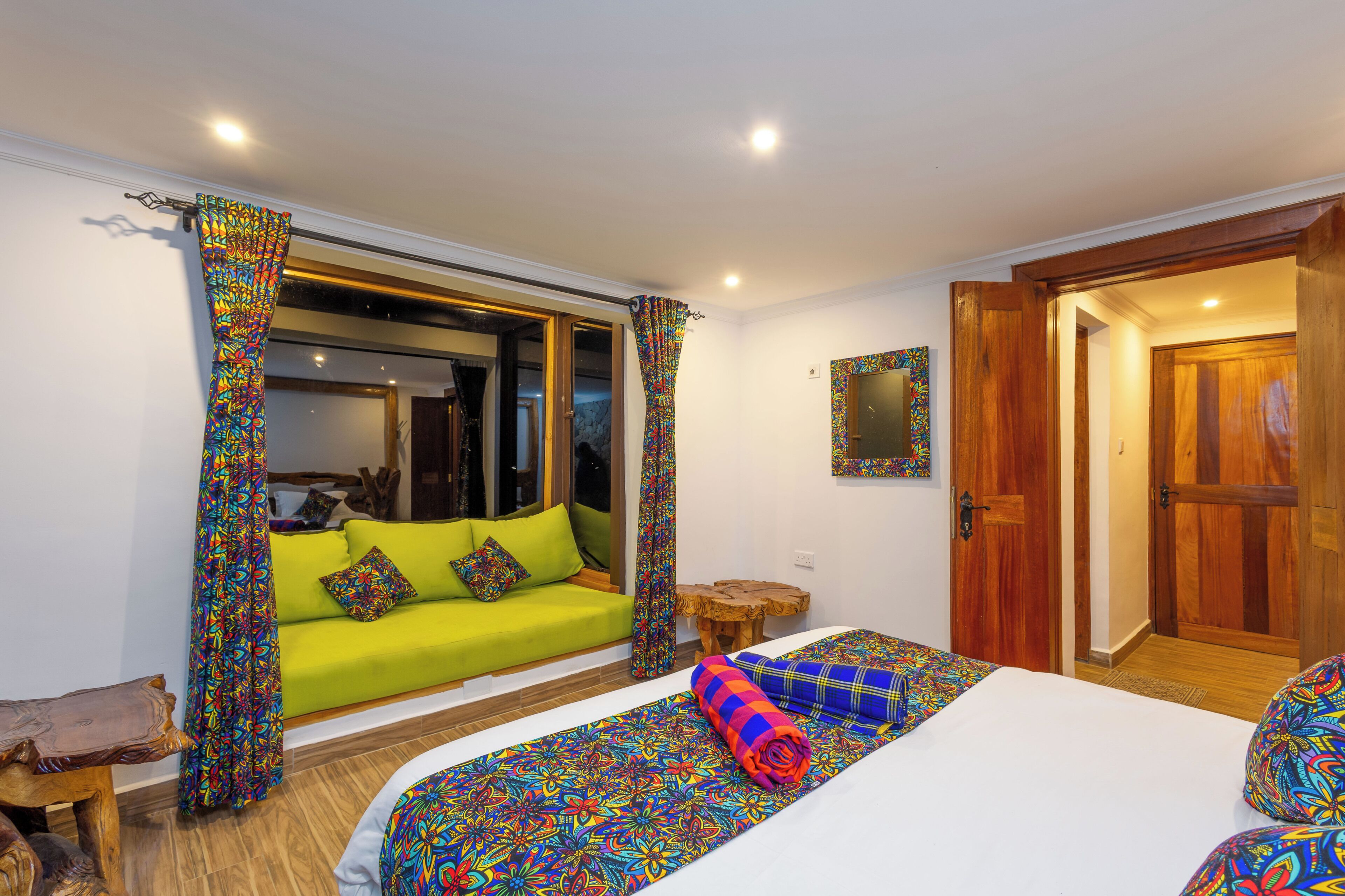 A room with a bed, a sofa, a wooden door, and a mirror.
