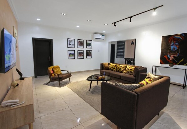 A modern living room with a sofa, armchair, coffee table, and a flat-screen TV.