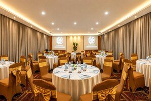 Un salón de conferencias con mesas redondas, sillas y una pantalla proyectora mostrando 'GB Diamond'.