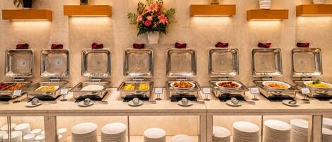 A buffet setup with multiple food stations, each with a glass container and a sign.