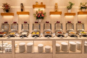 A buffet setup with multiple food stations, each with a glass container and a sign.