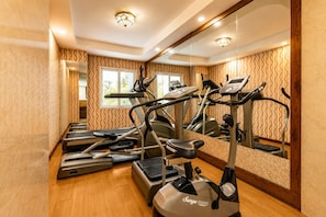 Un gimnasio con cintas de correr, bicicletas estáticas y un espejo grande.