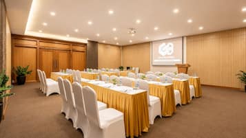A conference room with multiple tables and chairs, a projector screen, and a podium.