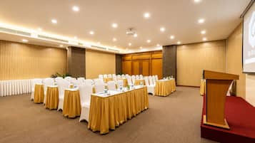A conference room with round tables, white chairs, and a podium.