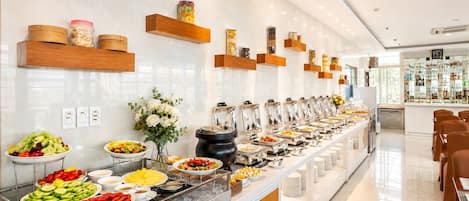 Un bufé con diversas opciones de comida, una decoración floral y una zona de bar con botellas.