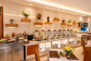 Ein Buffet mit verschiedenen Speiseauslagen, einem Sitzbereich mit Tischen und Zierpflanzen.
