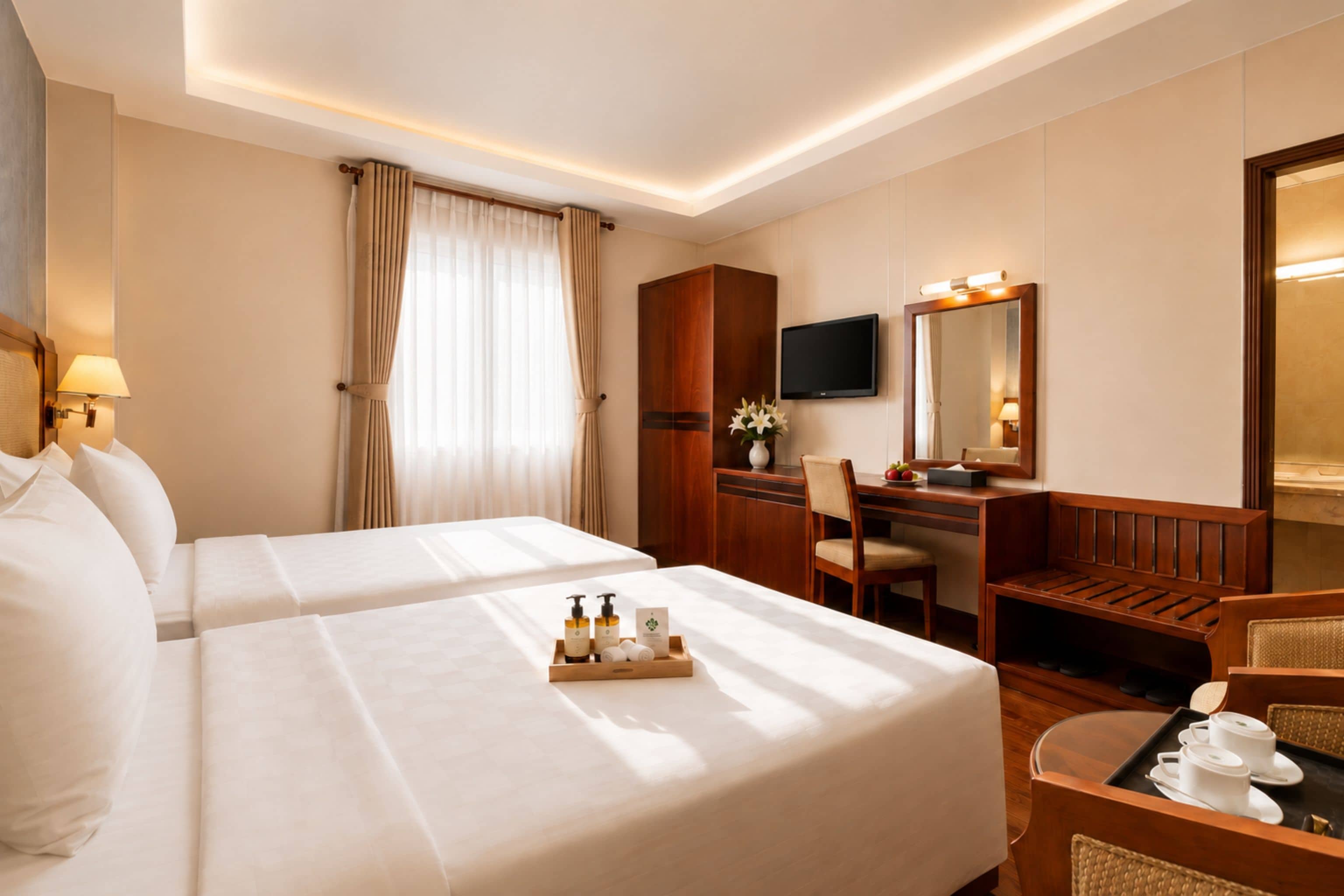 A hotel room with two beds, a desk, a chair, a television, and a mirror.