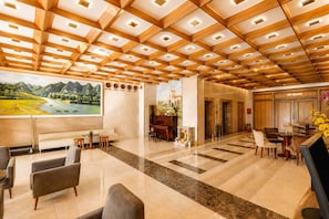 Un vestíbulo de hotel con techo de madera, un piano, una zona de estar y un cartel que indica 'VIP Room'.
